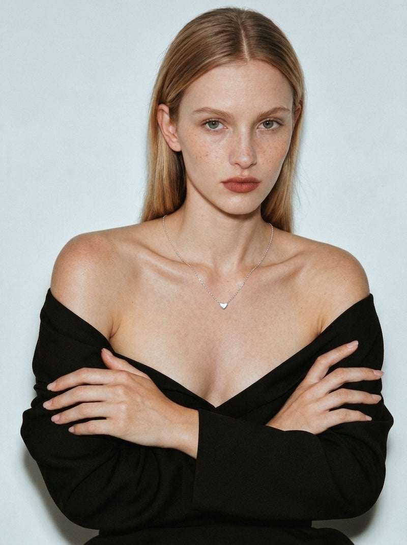 A silver chain necklace with a small heart-shaped pendant, displayed on a clean white background with an adjustable link extension chain shown below.